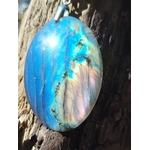 Pendentif labradorite ovale photographié sur bois naturel en forêt, reflets bleus lumineux et monture argentée, recentrage et protection subtile.