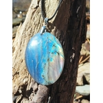 Zoom sur pendentif ovale en labradorite aux reflets bleus sur pierre naturelle en décor breton, bélière argentée et éclats irisés, clarté mentale et stabilité émotionnelle.