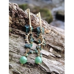 Boucles d’oreilles dorées pendantes en turquoise africaine sur bois texturé en forêt, perles bleu-vert marbrées et pampilles délicates, apaisement intérieur et expression fluide.