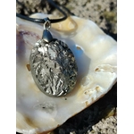 Pendentif pyrite naturelle sur coquillage en bord de mer en Bretagne, pierre aux reflets métalliques argentés avec cordon noir.
