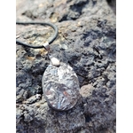 Gros plan sur pendentif pyrite naturelle sur roche claire en Bretagne, pierre métallisée argentée avec cordon noir, appréciée pour la détermination et l’enracinement.