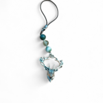 Bijou de téléphone Éole sur fond blanc, perles bleu clair et détails argentés, création Magic Gaïa évoquant la sérénité, la fluidité et l’équilibre intérieur.