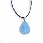 Pendentif calcite bleue naturelle en forme de goutte sur fond clair, pierre bleu laiteux aux nuances douces, apaisement et calme intérieur.