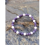 Bracelet Lépidolite Kunzite sur rocher en Bretagne, perles violettes et roses en pierres naturelles, apaisement émotionnel et douceur intérieure.