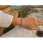 Bracelet Lépidolite Kunzite porté au poignet en extérieur près de la mer en Bretagne, bijou en pierres naturelles aux tons violets et rosés.
