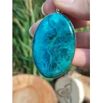Gros plan sur pendentif chrysocolle argent 925 tenu entre les doigts, pierre bleu vert lumineuse, sérénité émotionnelle et communication authentique.
