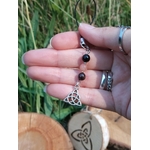 Bijou de téléphone Viking Triquetra en mise en situation naturelle, perles noires et rose tendre, harmonie et protection symbolique.