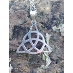 Pendentif Triquetra en argent 925 posé sur bois naturel en extérieur, bijou celtique ajouré avec chaîne argentée, harmonie, protection et équilibre intérieur.