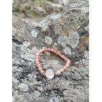Bracelet pierre de soleil femme sur pierre naturelle en bord de mer breton, bijou énergétique aux tons saumon cuivrés, vitalité, motivation et chaleur intérieure.