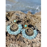 Boucles d’oreilles dorées éventail tissé bleu turquoise posées sur rochers en bord de mer en Bretagne, bijou bohème lumineux