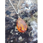 Pendentif Ambre baltique goutte sur roche en Bretagne, résine fossile miel orangé avec chaîne argentée, chaleur intérieure et vitalité douce.