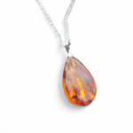 Pendentif Ambre baltique goutte sur fond blanc, résine fossile miel doré translucide avec bélière argentée, apaisement mental et confiance.
