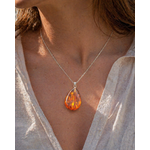 Pendentif Ambre baltique goutte porté sur chaîne argentée, bijou lumineux aux nuances cognac, réconfort émotionnel et énergie solaire.