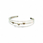 Bracelet jonc doré quadruple fils sur fond blanc, détails cœurs et strass lumineux, bijou ouvert élégant pour le poignet.