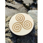 Plaque Triskell 10 cm sur rocher au bord de mer en Bretagne, motif celtique gravé pour équilibre et évolution.