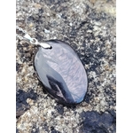 Pendentif Hyperstène ovale sur roche en Bretagne, pierre noire à reflets argentés, ancrage, protection symbolique et stabilité intérieure