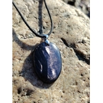 Pendentif Hyperstène ovale sur galet clair en bord de mer en Bretagne avec cordon noir, pierre naturelle sombre à reflets métallisés, ancrage et introspection