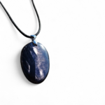 Pendentif Hyperstène ovale sur fond blanc avec cordon noir, pierre naturelle sombre à reflets métallisés, ancrage et introspection