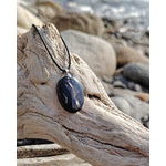 Pendentif Hyperstène posé sur bois flotté en Bretagne face à la mer, bijou en pierre naturelle pour ancrage et force intérieure