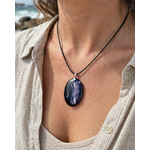 Pendentif Hyperstène porté sur peau en lumière naturelle au bord de mer en Bretagne, pierre de calme intérieur et de protection douce