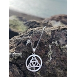 Gros plan sur pendentif Triquetra rond en argent 925 en Bretagne, médaillon celtique ajouré aux entrelacés délicats.