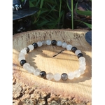 Bracelet Tourmaline noire et Quartz tourmaliné 6 mm sur rondin de bois, décor nature avec herbes, protection énergétique et ancrage.