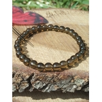 Bracelet Quartz fumé 6 mm sur fond naturel, perles brunes translucides aux reflets fumés, ancrage et clarté intérieure.