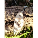 Porte-clés Sigile de Protection Physique suspendu à une écorce en forêt, mousse, fougère et lumière naturelle.