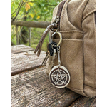 Porte clés pentacle en bois accroché à un sac beige en extérieur, mise en situation naturelle pour harmonie et recentrage.