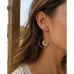 Boucle d’oreille lune portée en situation naturelle, lapis lazuli bleu et acier doré pour une touche élégante et intuitive.
