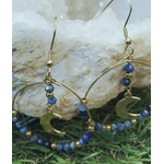Boucles d’oreilles lapis lazuli facetté posées près d’une pierre claire, créoles dorées avec lunes pour clarté et expression de soi.