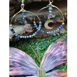 Boucles d’oreilles lune en lapis lazuli sur décor naturel avec papillon violet, création Magic Gaïa pour harmonie intérieure.