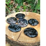 Galet merlinite mystique gabbro posé en décor naturel, pierre polie aux motifs uniques pour intuition et équilibre énergétique.