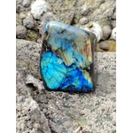 Labradorite polie aux éclats bleus sur surface minérale, forme libre naturelle pour recentrage et protection énergétique.