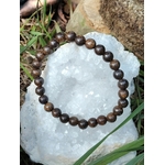 Bracelet en pierre bronzite posé dans une ambiance minérale, reflets bruns métallisés pour stabilité intérieure et maîtrise de soi.