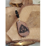 Face Triquetra du bijou de rétroviseur Magic Gaïa sur rondins de bois, gravure celtique et perles de tourmaline noire pour équilibre.