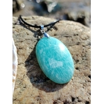 Gros plan du pendentif Amazonite sur roche claire, pierre polie du Pérou pour légèreté émotionnelle et intuition.