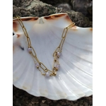 Bracelet fin en acier inoxydable doré présenté sur coquillage nacré, perles facettées violettes et éclat subtil.