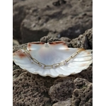 Bracelet acier inoxydable doré dans un grand coquillage blanc, bijou léger aux nuances mauves et style chic.