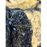 Bracelet doré à perles lavande sur roche côtière, bijou délicat pour une allure douce et féminine.