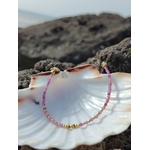 Bracelet Tourmaline rose présenté dans une coquille nacrée en bord de mer, création fine aux nuances poudrées.