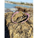 Bracelet Tourmaline rose facettée sur roche en Bretagne, cuivre plaqué or et mer floutée pour une allure lumineuse.