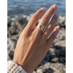 Bague Améthyste portée au doigt face à la mer, bijou doré ajustable au relief martelé pour intuition et élégance.
