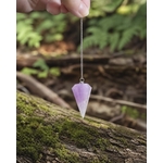 Pendule Améthyste suspendu en main dans un décor forestier, outil spirituel pour guidance et perception subtile.