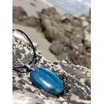 Pendentif Labradorite bleue allongé sur roche côtière en Bretagne, reflets bleus pour clarté mentale et protection.