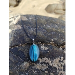 Pendentif Labradorite bleue sur roche bretonne avec sable en arrière-plan, cordon noir pour stabilité et protection.