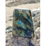 Forme libre Labradorite sur roche du littoral breton, éclats bleus verts pour présence, recul et équilibre émotionnel.