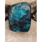 Labradorite forme libre sur tranche de bois, veines sombres et lumière turquoise pour recentrage et bouclier énergétique.