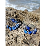 Vue rapprochée des boucles d’oreilles Lapis-Lazuli sur pierre marine en Bretagne, montage créatif avec chips bleues non régulières.