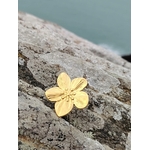 Bague fleur dorée réglable en acier inoxydable sur rocher côtier breton, motif floral texturé et finition or 18K pour un style solaire.